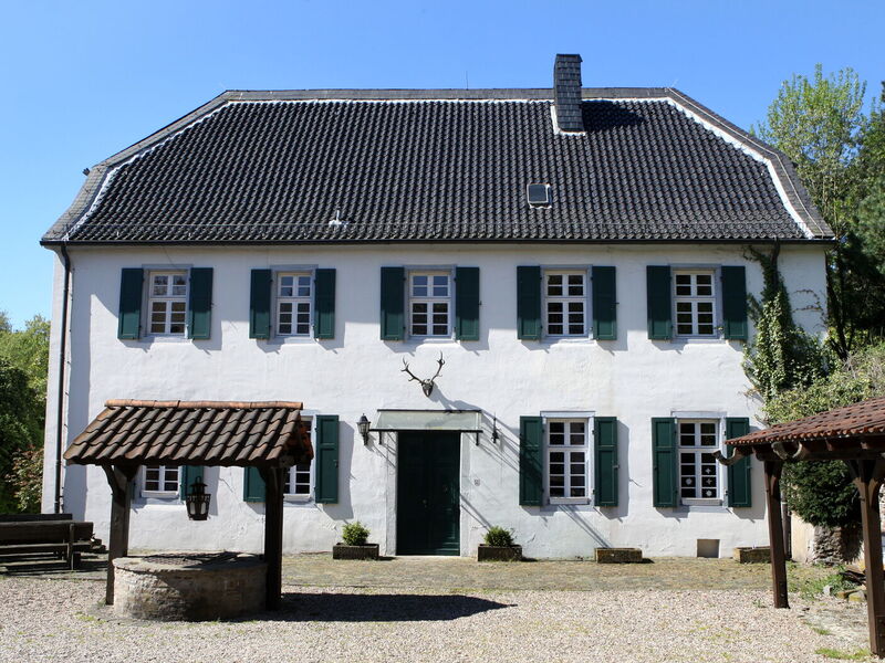 Das historische Gebäude des Forsthauses Steinhaus mit Ziehbrunnen im Vordergrund und Hirschgeweih über der Eingangstür